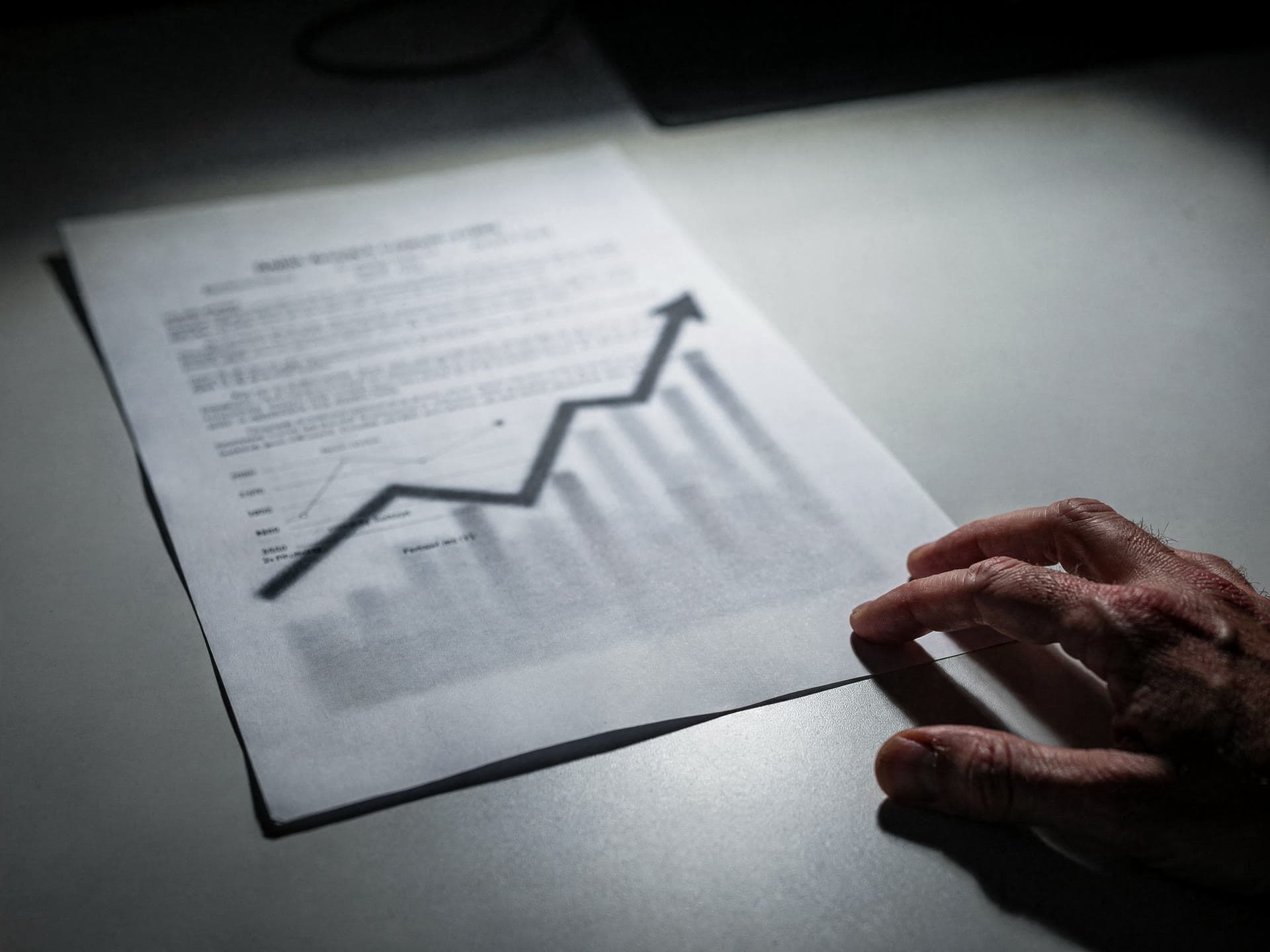 A printed merchant processing statement on a desk with a climbing fee line