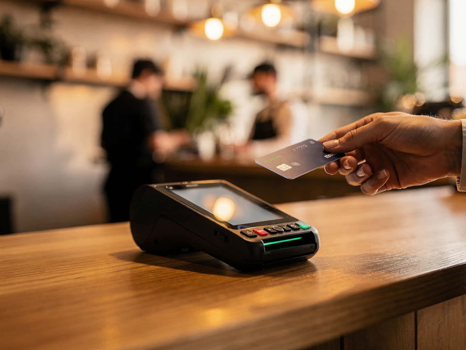 A busy modern small-business interior with a card terminal at the counter in warm light