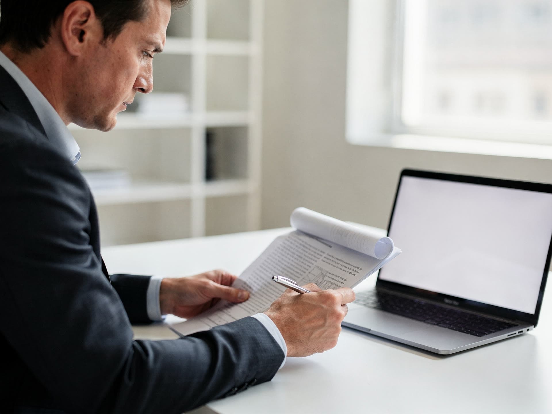 A consultant reviewing a processing statement line by line at a laptop